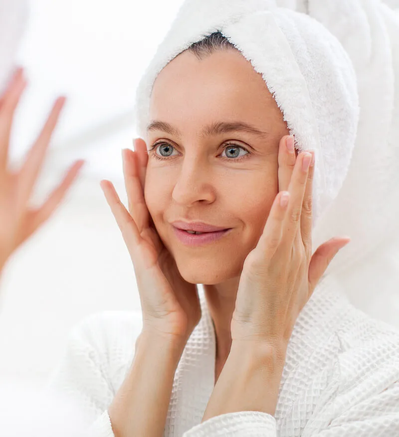 Woman in a towel turban resting her hands against her cheeks