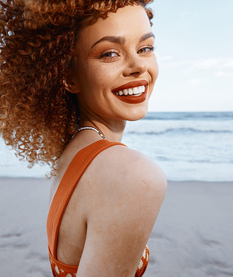 woman with red curly hair at the beach