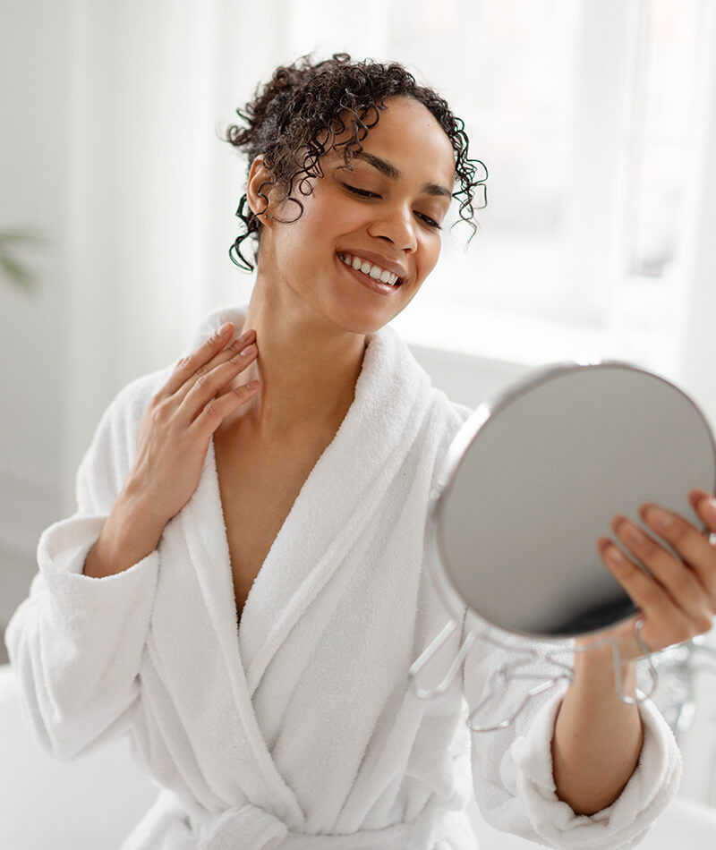 woman looking at her neck in the mirror